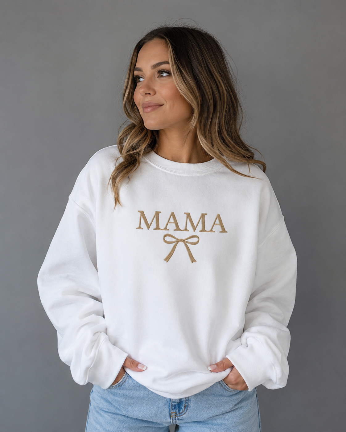 Close-up of woman wearing a white Mama bow sweatshirt from Soul Kreations Luxe featuring gold embroidered lettering and bow detail. ✨