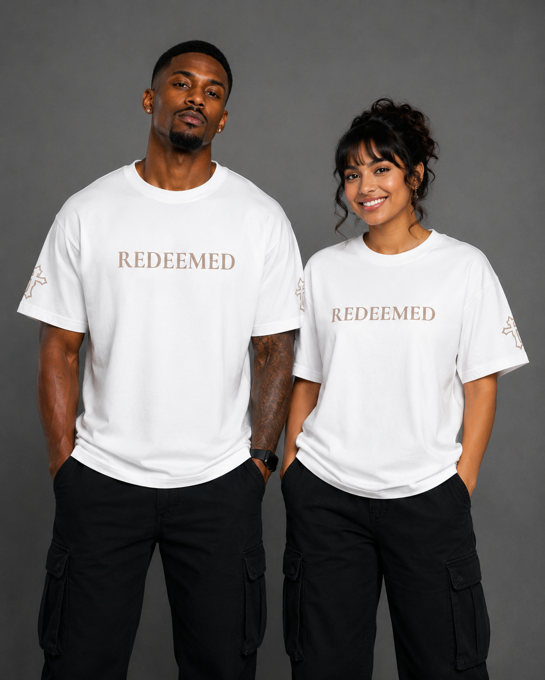 Two models wearing white Redeemed T-shirts from the Soul Kreations Luxe Promise Collection featuring embroidered Redeemed lettering and cross sleeve details. ✨