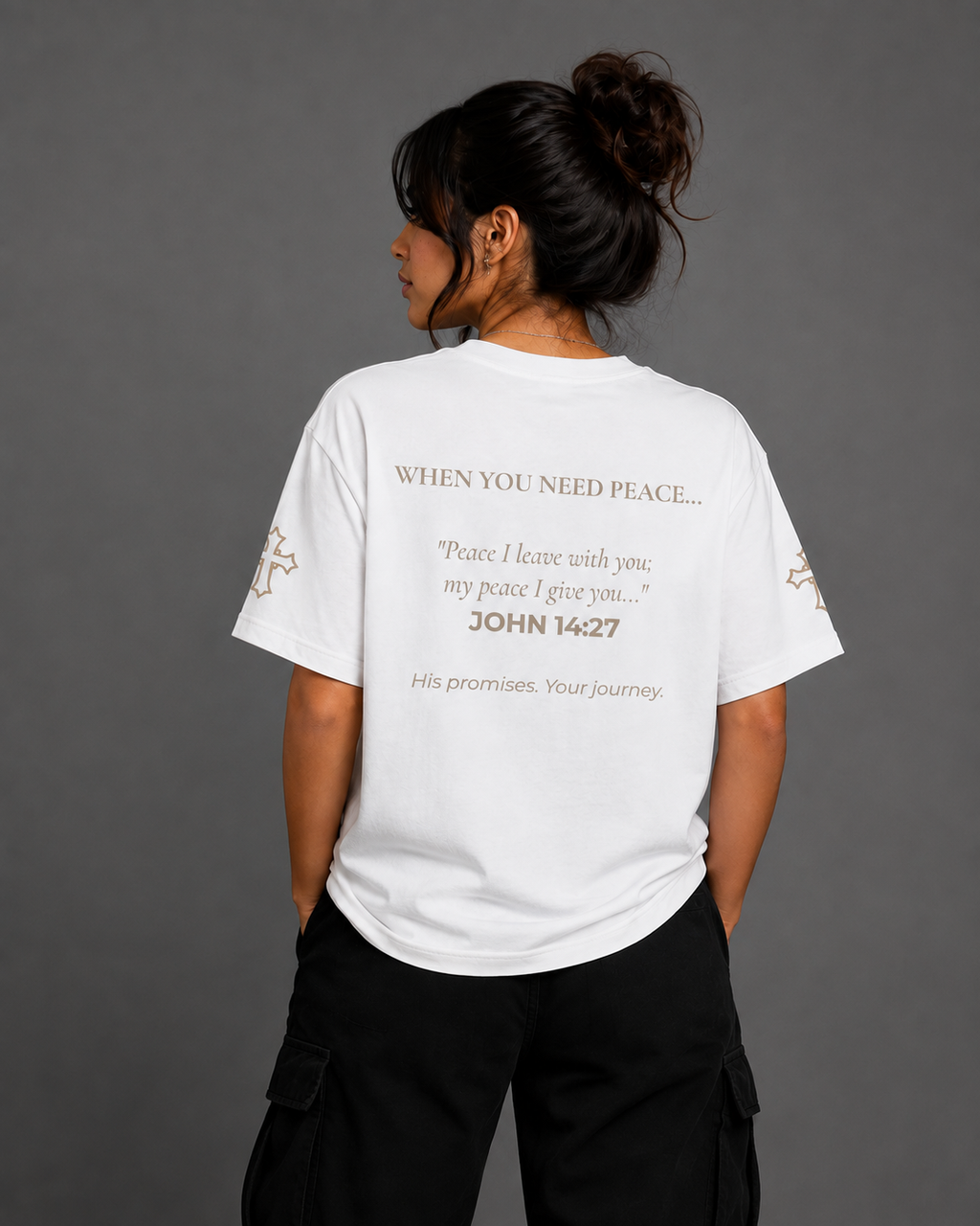Female model wearing white Peace T-shirt from the Soul Kreations Luxe Promise Collection, featuring John 14:27 scripture printed on the back and embroidered cross details on the sleeves.