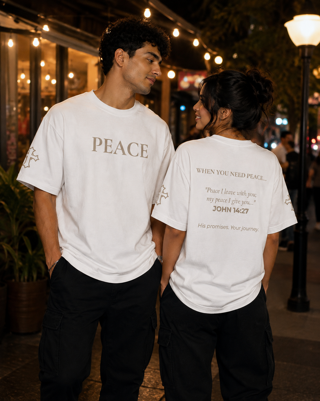 Male and female models wearing white Peace T-shirts from the Soul Kreations Luxe Promise Collection, featuring embroidered PEACE chest and cross sleeve details with John 14:27 scripture printed on the back.