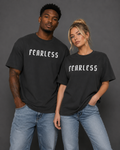 Male and female models wearing charcoal “FEARLESS” graphic T-shirts with blue jeans against a gray studio background.