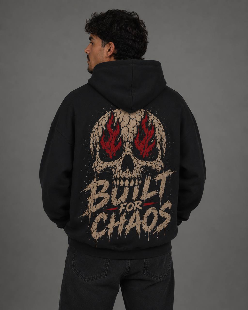 Back view of a male model wearing a black “Built for Chaos” hoodie featuring a large distressed skull graphic with red flames.