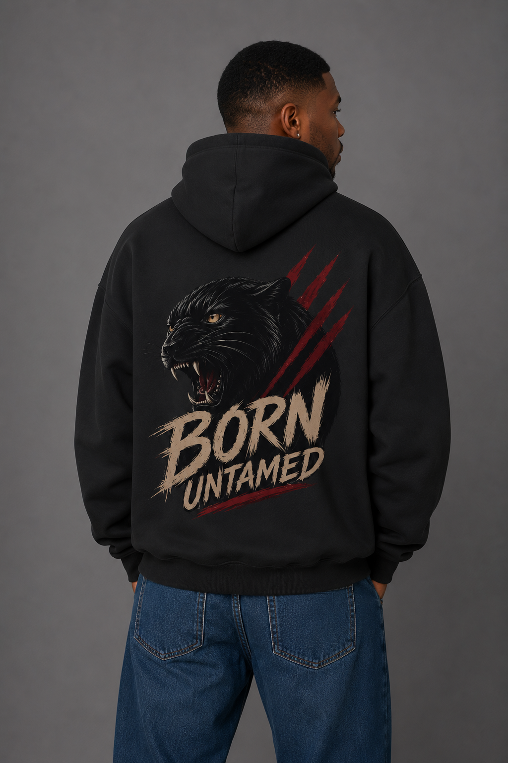 Male model showcasing the back of a black “Born Untamed” hoodie featuring a roaring black panther, red claw marks, and bold distressed lettering.