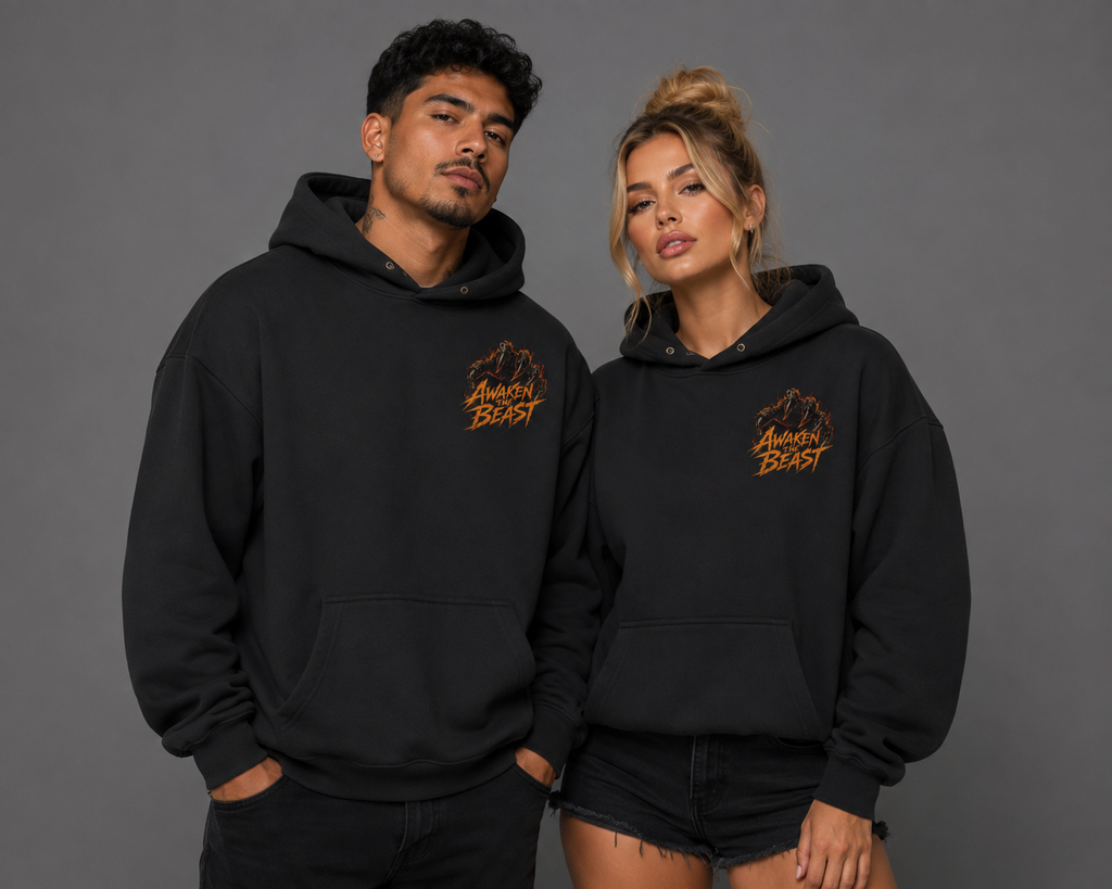 Male and female models wearing black “Awaken the Beast” hoodies with small fiery orange chest graphics, photographed together against a gray studio background.