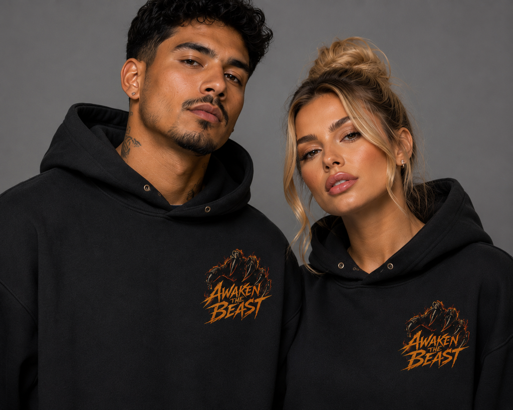 Close-up of male and female models wearing black “Awaken the Beast” hoodies with fiery orange chest graphics against a gray studio background.
