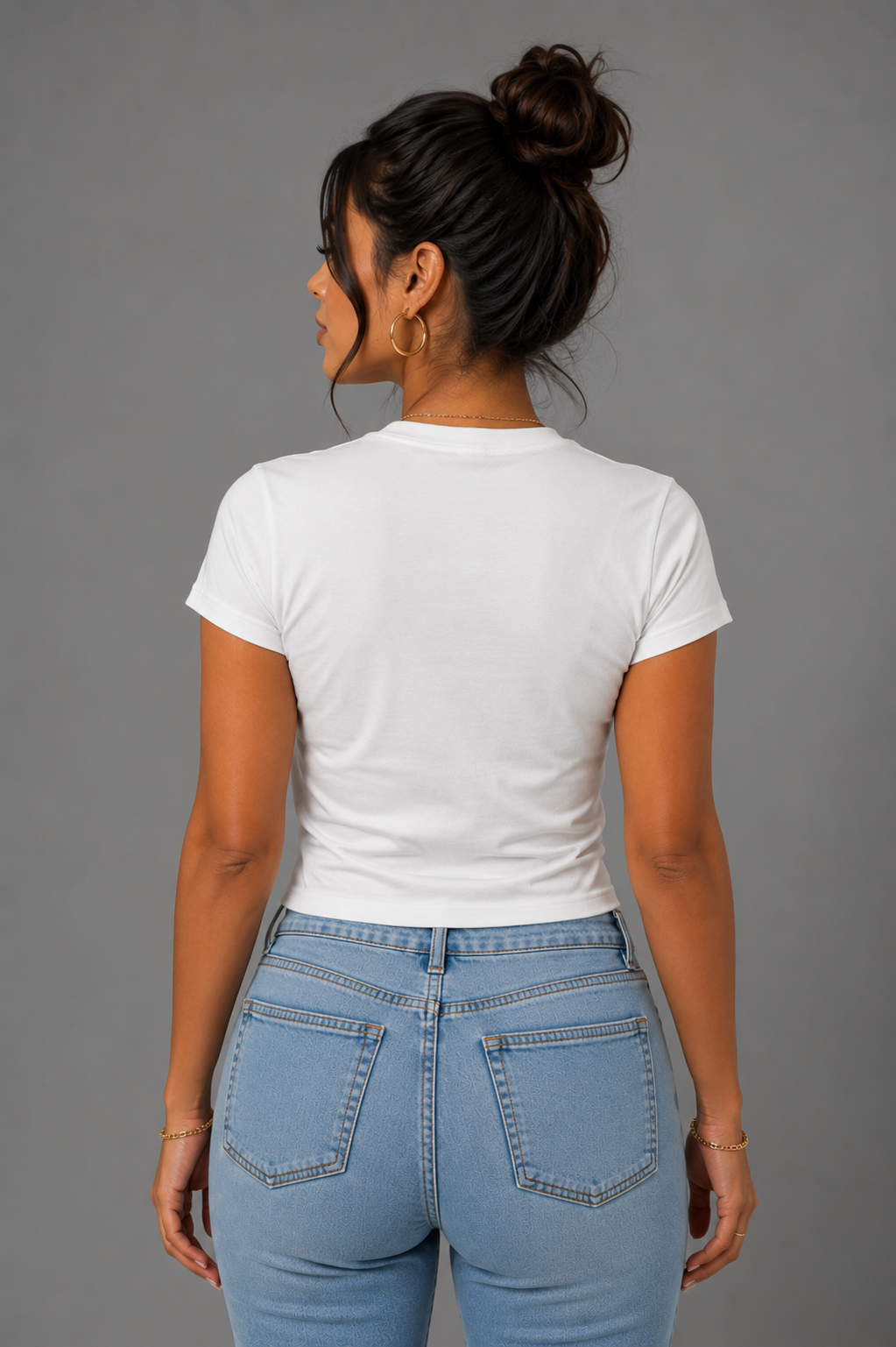 Back view of woman modeling a fitted white T-shirt with light blue jeans, showing the clean plain back and slim fit of the shirt.