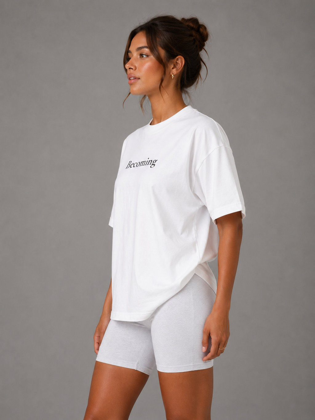 Side view of woman wearing white oversized Becoming graphic T-shirt