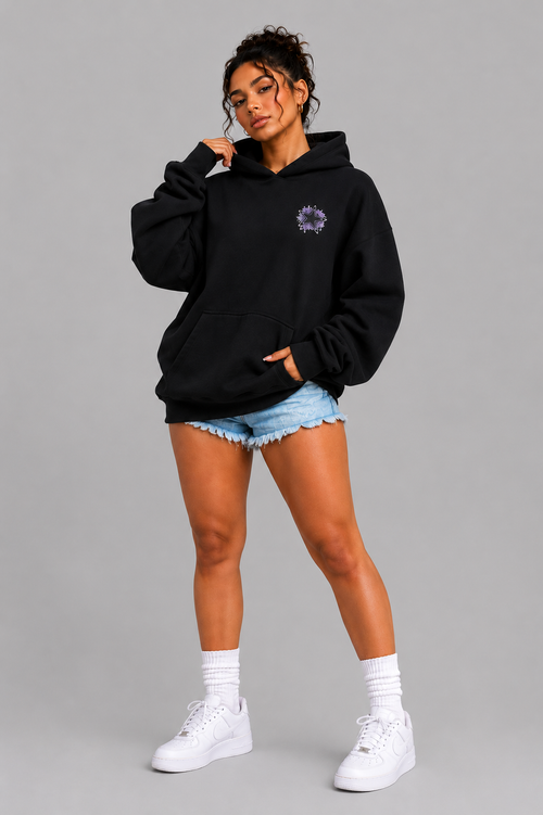 Woman wearing black oversized hoodie with purple chest graphic on a gray background