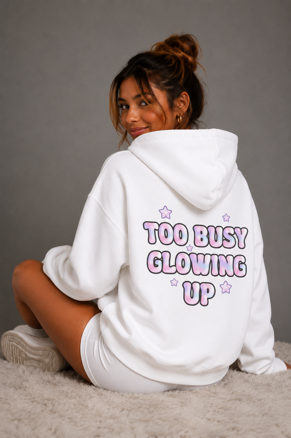 Woman modeling white Too Busy Glowing Up hoodie with pink star graphics on back