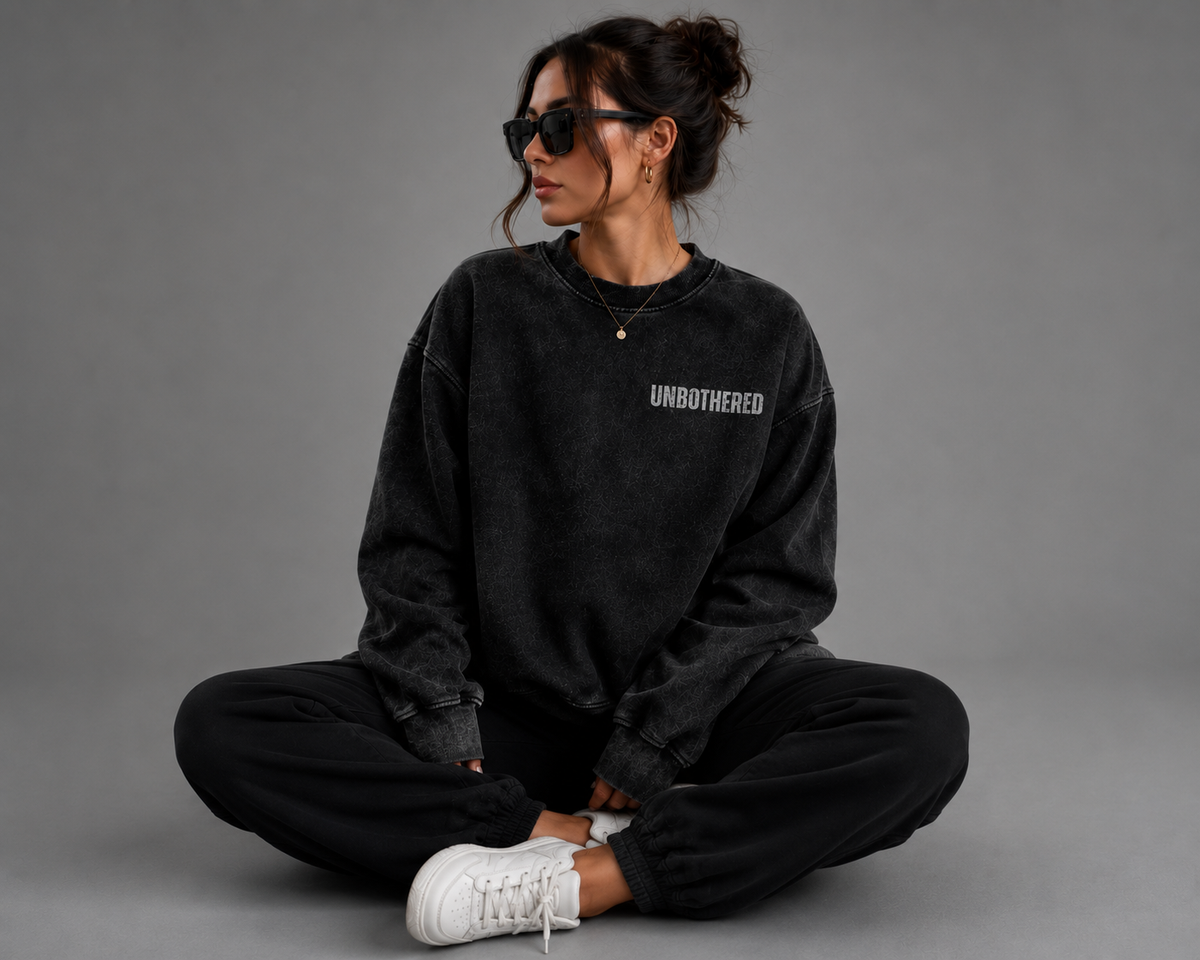 Woman sitting cross-legged in black washed Unbothered embroidered oversized sweatshirt