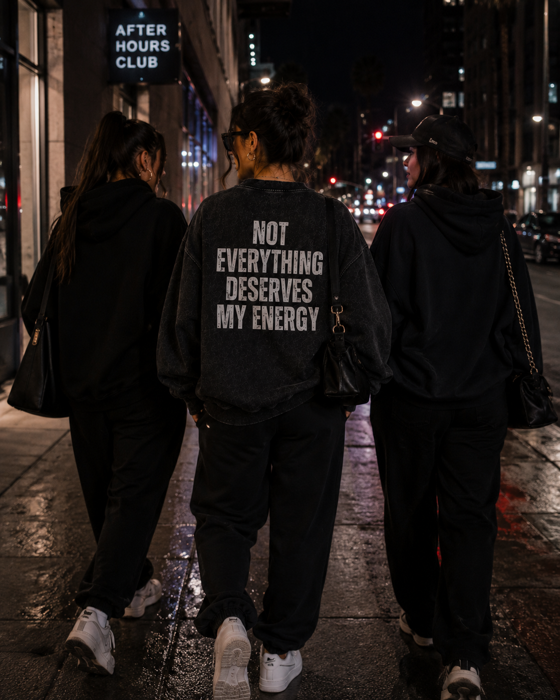 Woman wearing black Unbothered sweatshirt with “Not Everything Deserves My Energy” back graphic on a city night out