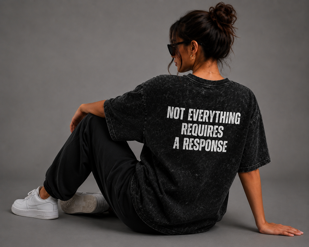 Woman wearing black washed oversized T-shirt with “Not Everything Requires a Response” graphic on the back