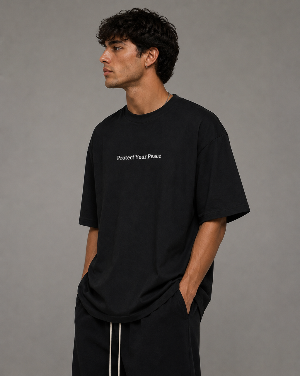 Side view of man wearing black Protect Your Peace oversized T-shirt by Soul Kreations Luxe