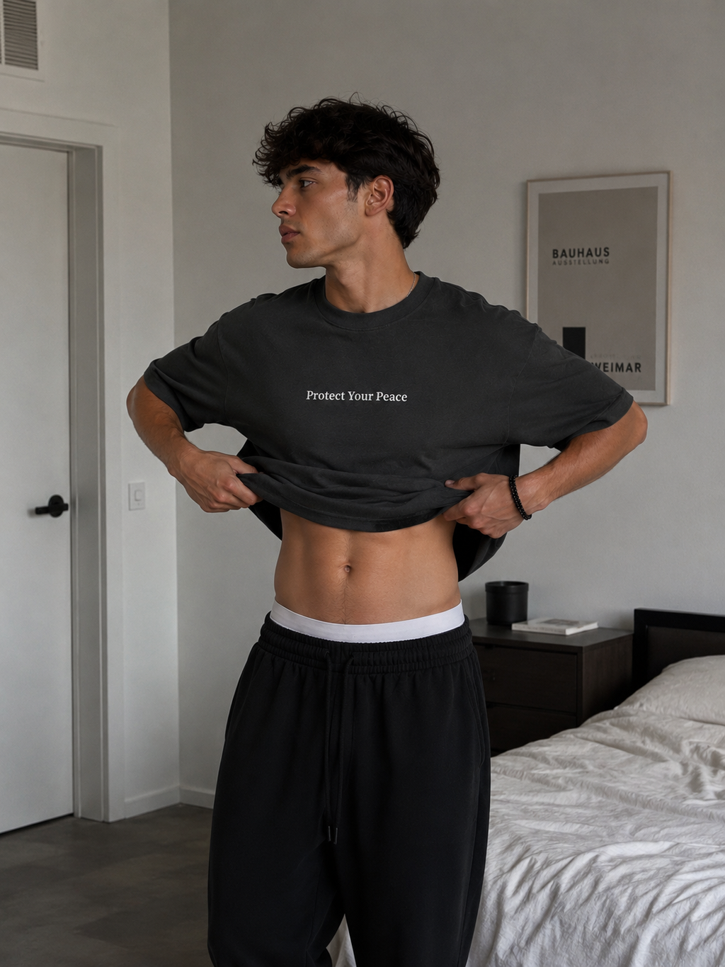 Man wearing black Protect Your Peace oversized T-shirt in a casual indoor lifestyle setting