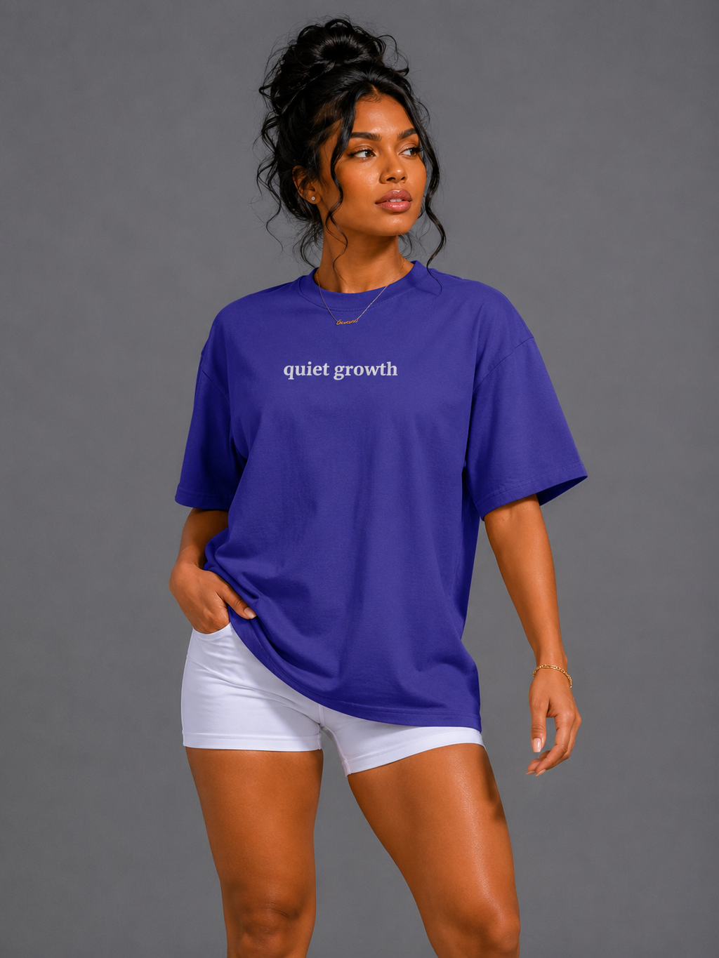 Woman wearing purple Quiet Growth oversized T-shirt on a gray background