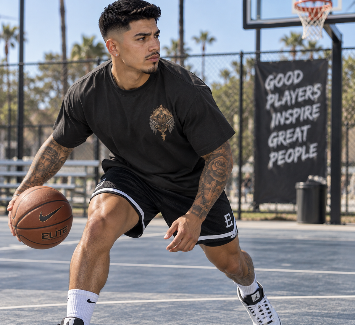 Male model playing basketball while wearing the Fallen Angels charcoal T-shirt with gothic-inspired cross and angel details.