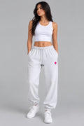 Woman wearing heather gray sweatpants with embroidered pink flower on the thigh